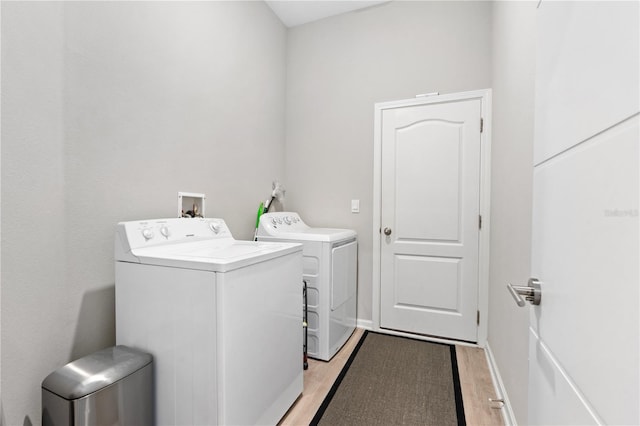 laundry room featuring washer and clothes dryer and light hardwood / wood-style flooring