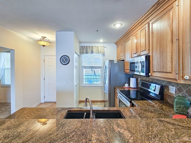 kitchen with sink, backsplash, stainless steel appliances, and a textured ceiling