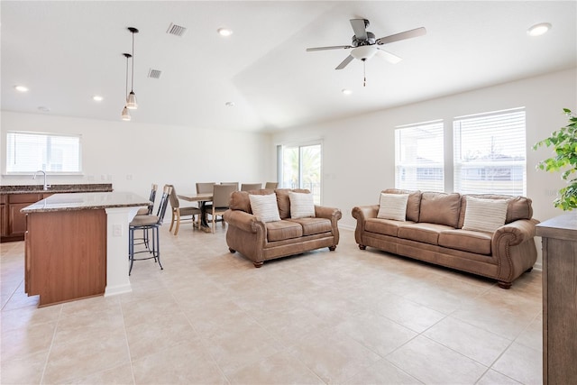 tiled living room featuring ceiling fan, lofted ceiling, and sink