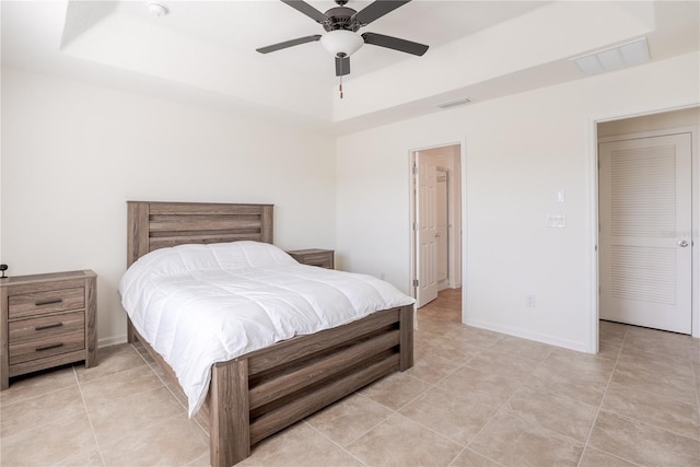 tiled bedroom featuring ceiling fan and a tray ceiling