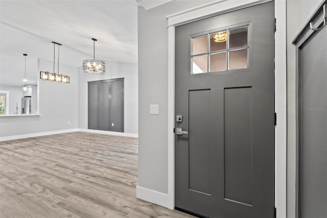 entrance foyer with lofted ceiling, a chandelier, and light wood-type flooring