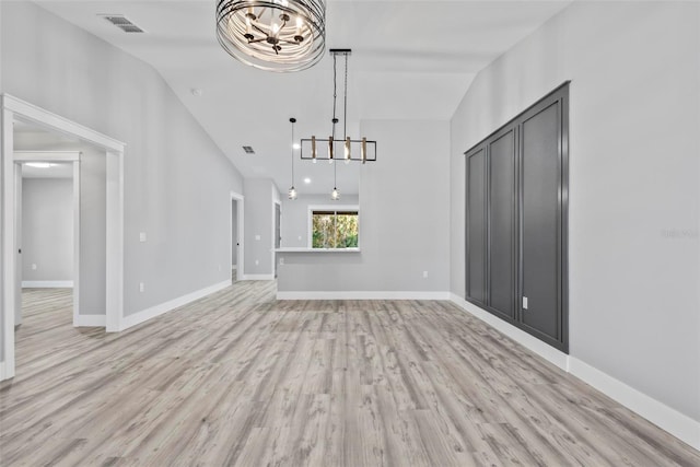 unfurnished living room featuring vaulted ceiling, a notable chandelier, and light hardwood / wood-style floors