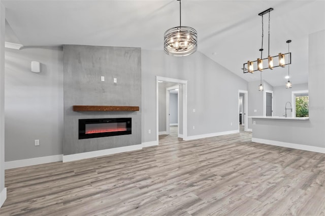 unfurnished living room with high vaulted ceiling, sink, light hardwood / wood-style floors, and a notable chandelier