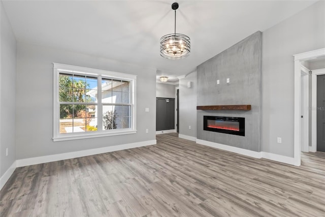 unfurnished living room featuring a notable chandelier and light hardwood / wood-style floors