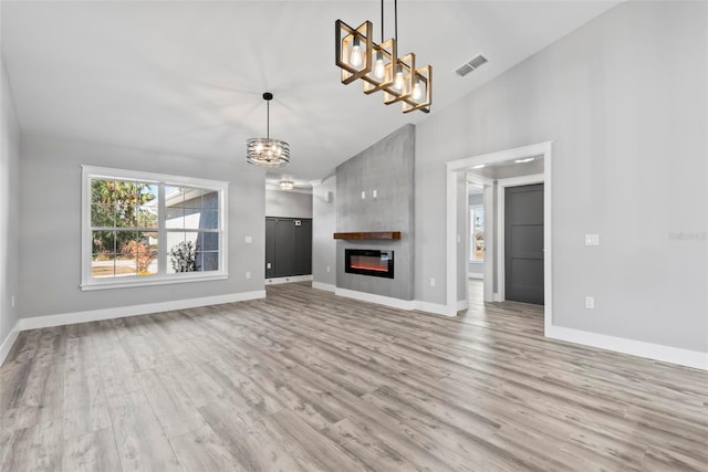 unfurnished living room featuring a notable chandelier, high vaulted ceiling, and light hardwood / wood-style flooring