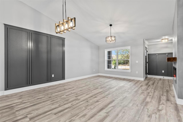 unfurnished living room featuring light hardwood / wood-style flooring, vaulted ceiling, and an inviting chandelier