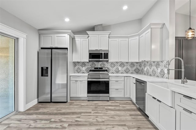 kitchen featuring white cabinetry, sink, decorative backsplash, hanging light fixtures, and stainless steel appliances