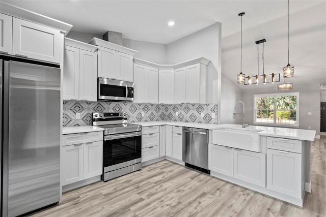 kitchen featuring white cabinetry, appliances with stainless steel finishes, decorative light fixtures, and sink