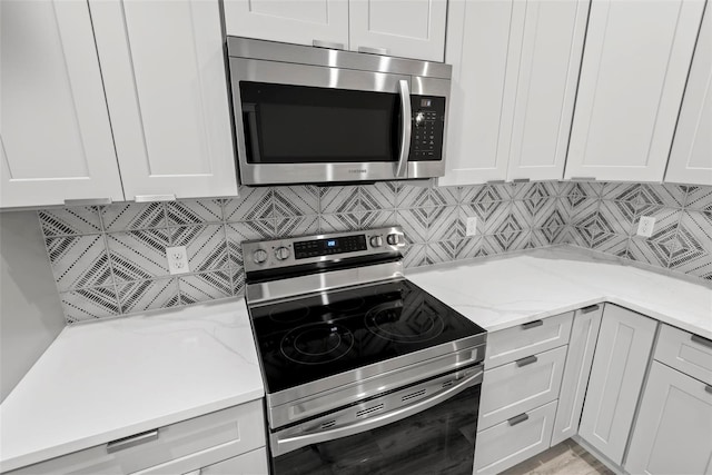 kitchen with white cabinetry, light stone counters, and appliances with stainless steel finishes