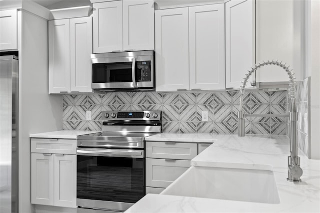 kitchen with white cabinetry, light stone counters, and appliances with stainless steel finishes