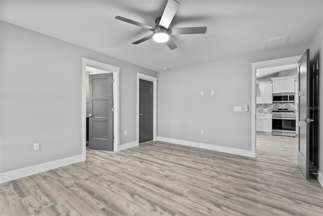 unfurnished bedroom with ceiling fan, a walk in closet, connected bathroom, and light hardwood / wood-style floors