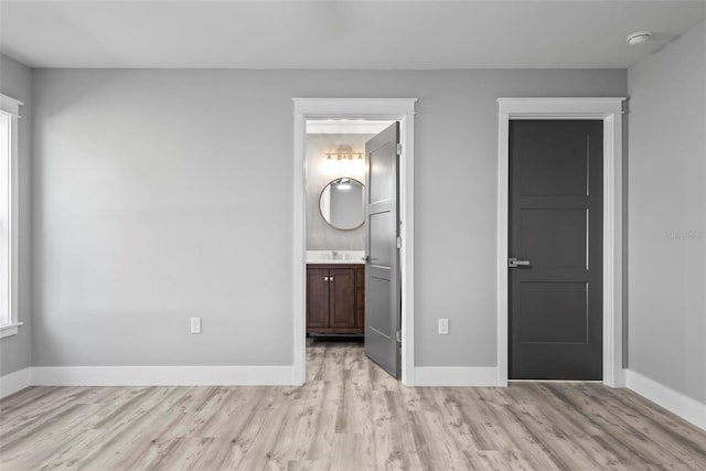 unfurnished bedroom featuring connected bathroom and light hardwood / wood-style flooring