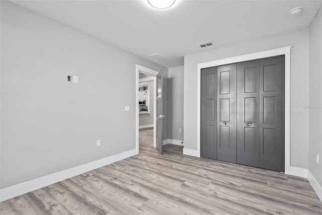 unfurnished bedroom with light hardwood / wood-style floors and a closet