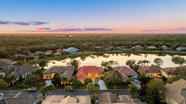 aerial view at dusk with a water view and a residential view