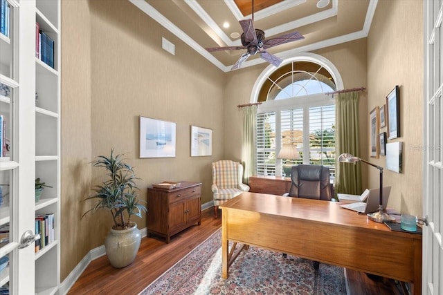 office featuring baseboards, a tray ceiling, wood finished floors, and crown molding