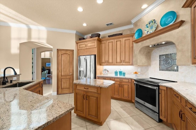 kitchen with arched walkways, a kitchen island, light stone counters, stainless steel appliances, and a sink