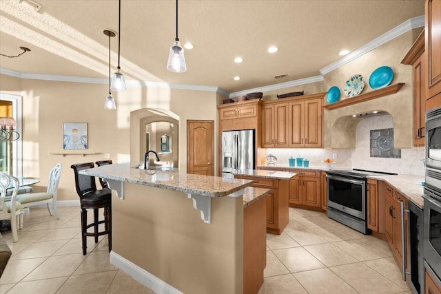 kitchen featuring light tile patterned floors, appliances with stainless steel finishes, a sink, and a kitchen island with sink