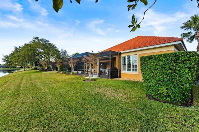 view of yard with a lanai and a water view