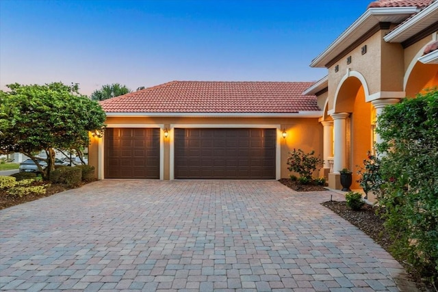 garage at dusk with decorative driveway