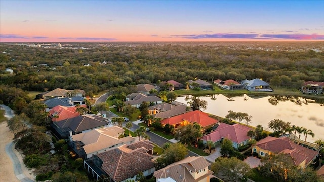 aerial view at dusk featuring a water view and a residential view