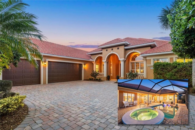 mediterranean / spanish home with decorative driveway, stucco siding, an in ground hot tub, a garage, and a tiled roof