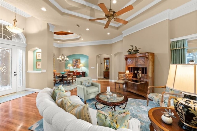 living room with a tray ceiling, arched walkways, crown molding, and wood finished floors