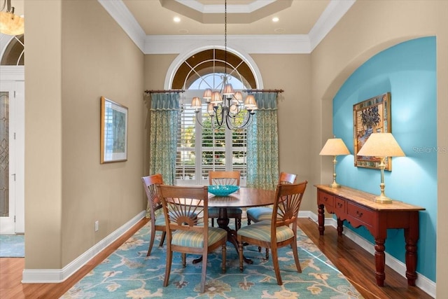 dining area with ornamental molding, wood finished floors, baseboards, and an inviting chandelier