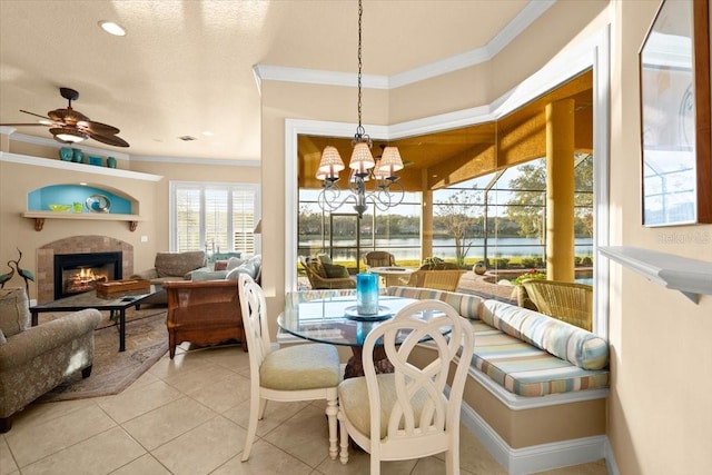 sunroom / solarium with a water view, a tiled fireplace, and ceiling fan with notable chandelier