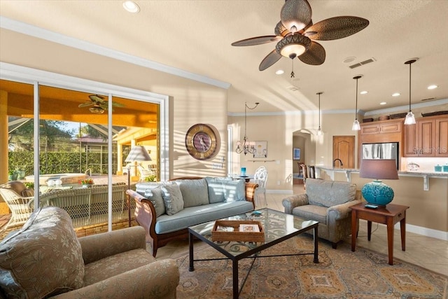 living room featuring light tile patterned floors, visible vents, baseboards, crown molding, and ceiling fan with notable chandelier