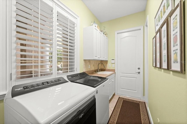 laundry area with cabinet space, light tile patterned floors, separate washer and dryer, and a sink