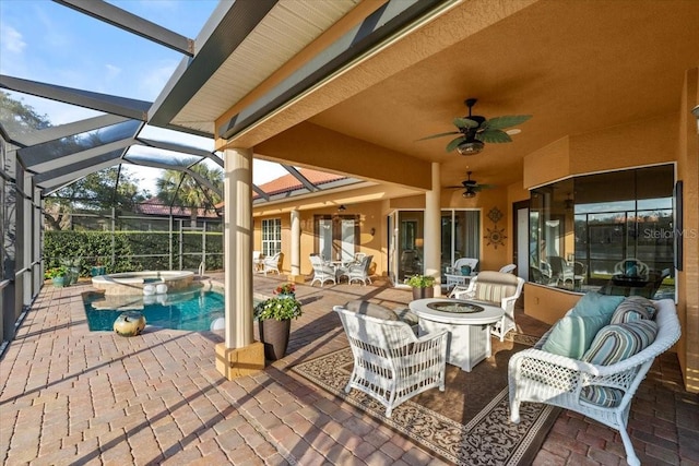 view of patio featuring glass enclosure, a pool with connected hot tub, a fire pit, and a ceiling fan