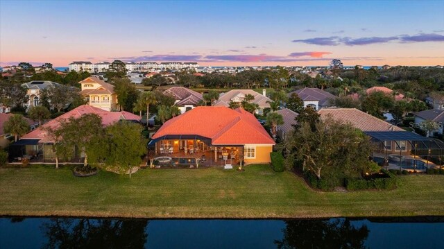 aerial view at dusk featuring a water view and a residential view