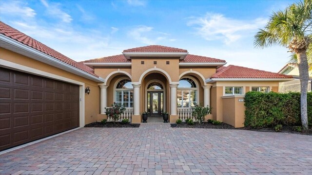 exterior space with decorative driveway, a tile roof, french doors, and stucco siding