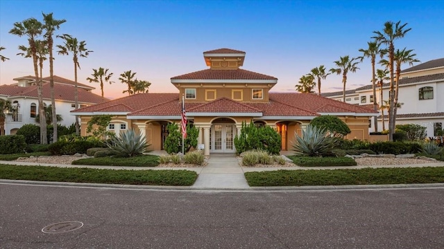 view of front facade featuring french doors, a tile roof, and stucco siding