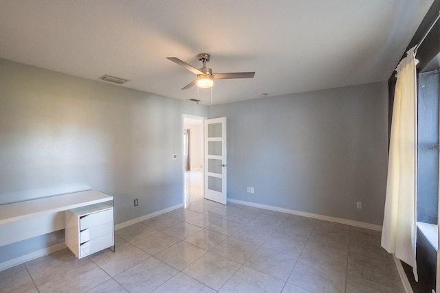 spare room with ceiling fan and light tile patterned floors