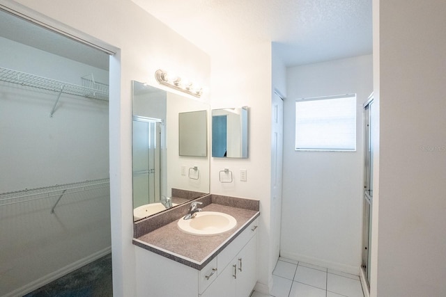 bathroom featuring tile patterned flooring, vanity, and walk in shower