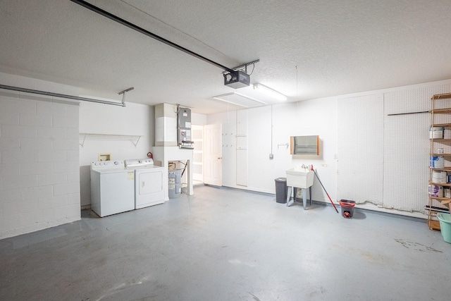 garage featuring washing machine and clothes dryer, a garage door opener, and sink