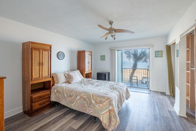 bedroom with access to exterior, a ceiling fan, dark wood-style floors, and a textured ceiling