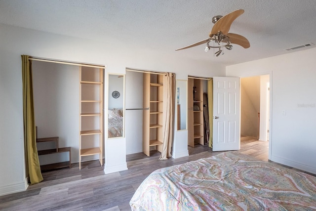 bedroom featuring a ceiling fan, visible vents, dark wood finished floors, and a textured ceiling