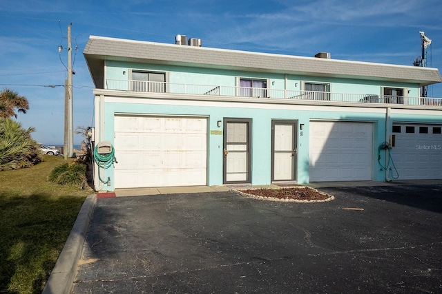 view of front of property with a garage, a balcony, and stucco siding