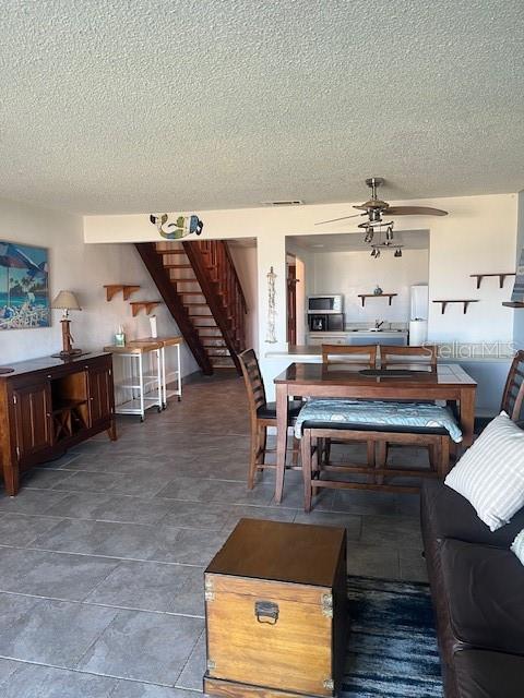 living area with stairs, ceiling fan, and a textured ceiling