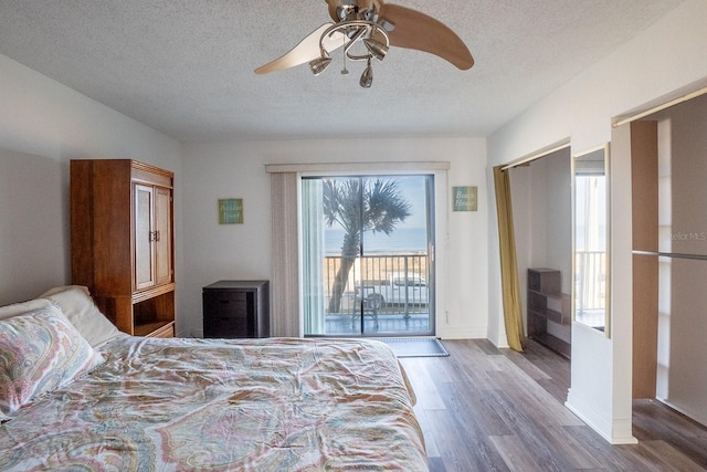 bedroom with a textured ceiling, wood finished floors, a ceiling fan, baseboards, and access to outside