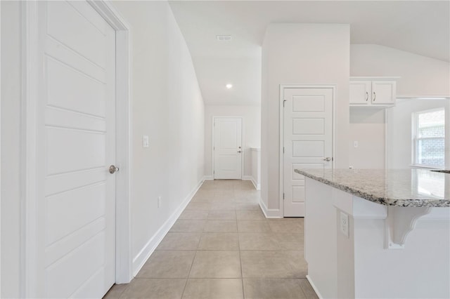 corridor featuring vaulted ceiling and light tile patterned floors