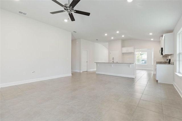 unfurnished living room featuring vaulted ceiling, ceiling fan, sink, and light tile patterned floors