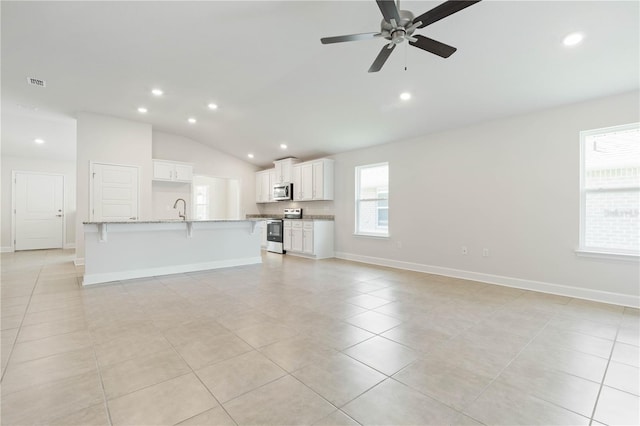 unfurnished living room featuring ceiling fan, lofted ceiling, sink, and light tile patterned floors