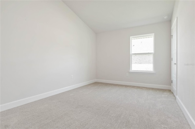 carpeted empty room with lofted ceiling