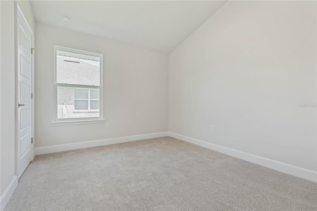 spare room with light colored carpet and vaulted ceiling