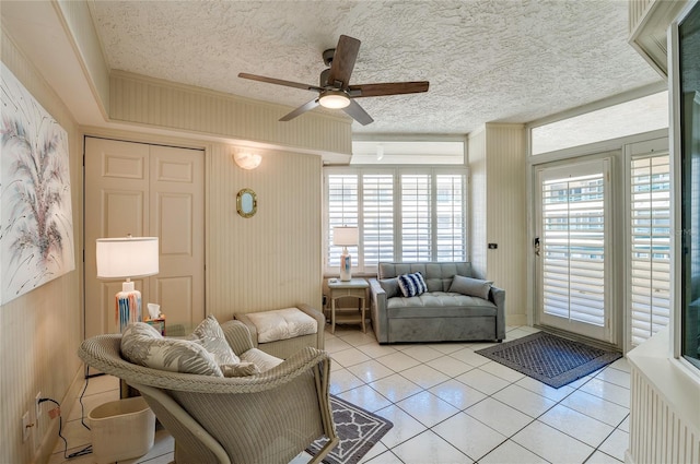 living room featuring ceiling fan, light tile patterned floors, and a textured ceiling