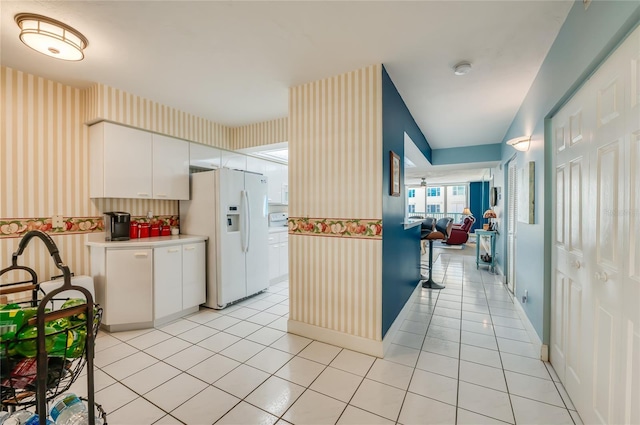 kitchen featuring light tile patterned flooring, white refrigerator with ice dispenser, and white cabinets