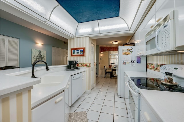 kitchen with white cabinetry, sink, light tile patterned floors, a raised ceiling, and white appliances